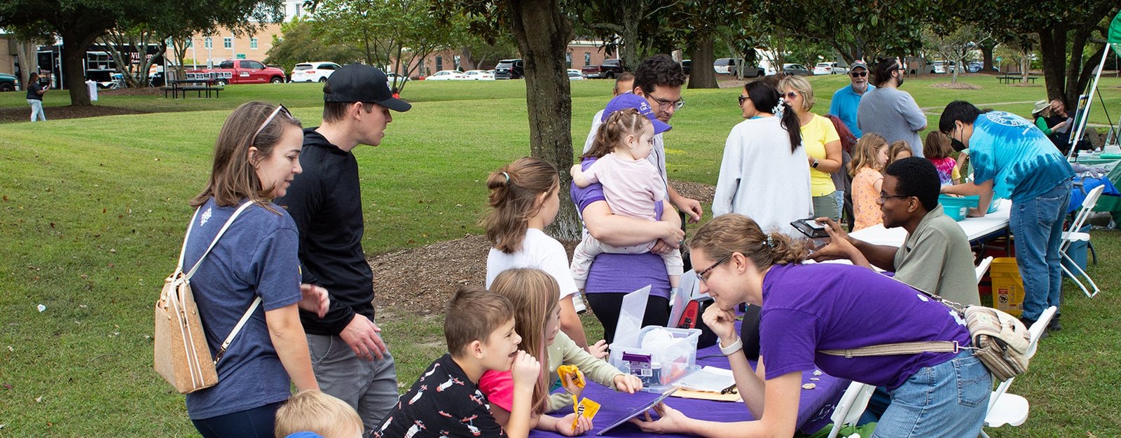 Families and children from the local community visit a display table with East Carolina University students outside on the Town Common lawn in Greenville, North Carolina, in 2023.